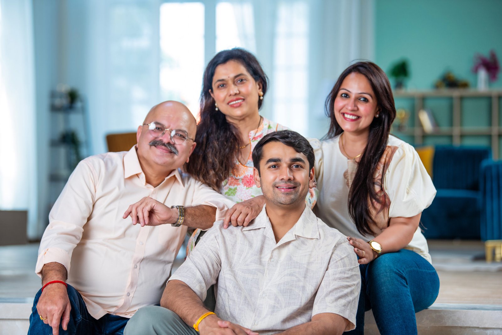 Indian family of four posing for a group photo in living room at modern home