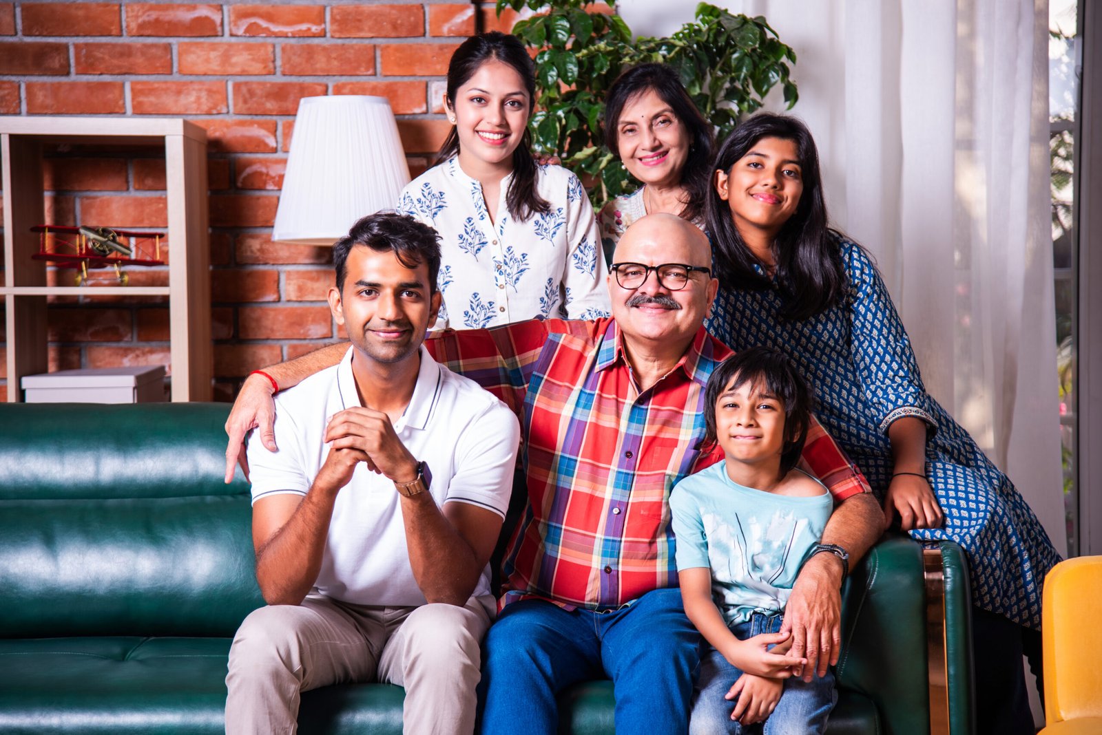 Group photograph of multigenerational Indian asian family sitting on sofa in living room